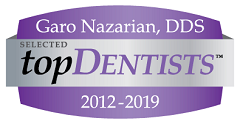 The image features a logo with text elements. It includes a graphic with a ribbon design at the top, inside which is a name  Garo Nazarian,  followed by the title  DDS.  Below this, there s a badge that reads  TOP DENTISTS  and the years  2012-2019.  The logo has a purple background with white text and a silver emblem.