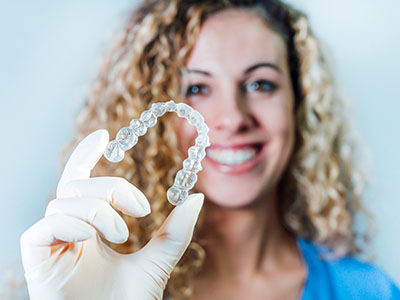 Woman holding up dental implant with white glove.