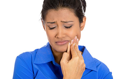 A woman with dark hair holding her face, seemingly in distress or pain.