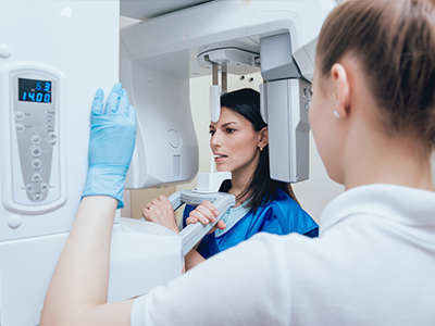 A woman using a dental scanner, with another person observing, set against a background that suggests a medical or dental environment.