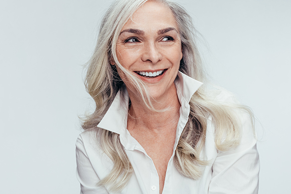 The image shows a woman with short hair smiling at the camera.