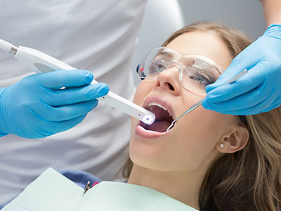 A woman receiving dental care with a dental hygienist using a device to clean her teeth.