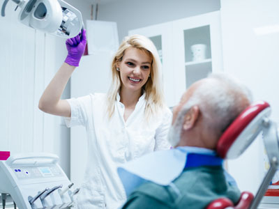 A dental professional is assisting an elderly patient with dental care equipment.