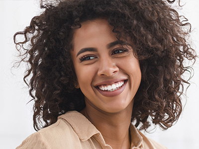 The image features a person with curly hair smiling at the camera.