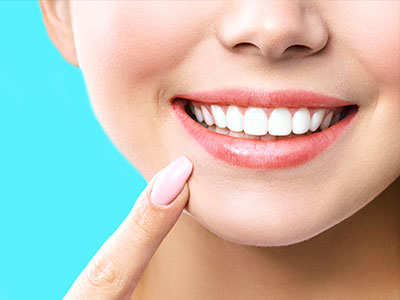 The image shows a close-up of a person s face with a smile, highlighting their teeth and lips, against a blue background.